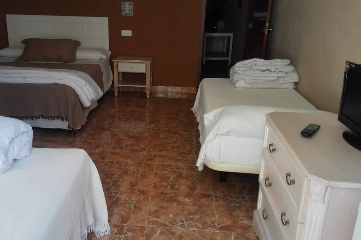 Ein Hotelzimmer mit zwei Betten, einem Fernseher, einem Schminktisch und einem kleinen Tisch.