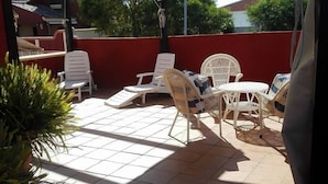 Un espace extérieur aménagé en terrasse, avec des chaises en plastique blanches et une petite table ronde.