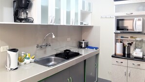 A modern kitchen with a stainless steel sink, a coffee maker, a microwave, and cabinets. - Eral Apartments Lima (Lima)