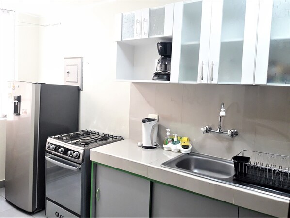 A compact kitchen with a gas stove, oven, and a coffee maker on the countertop.