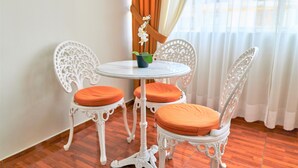 A room with a round table and two chairs with orange cushions, a potted orchid on the table, and a window with curtains. - Eral Apartments Lima (Lima)