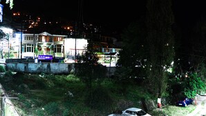 A hotel with multiple floors, a prominent tower, and a well-lit facade. - Hotel Suntejpaza (Nainital)