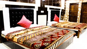 A hotel room with two beds, each with a patterned bedspread and a black headboard. - Hotel Suntejpaza (Nainital)