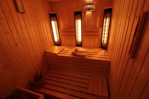 A wooden sauna with benches and a bench seat, a towel on one bench, and a towel rack. - Villa Merry Spa & Wellness (Swinoujscie)