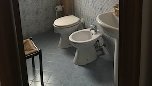A small bathroom with a toilet, bidet, and sink, tiled walls, and a window. - Egesta (Castellammare del Golfo)
