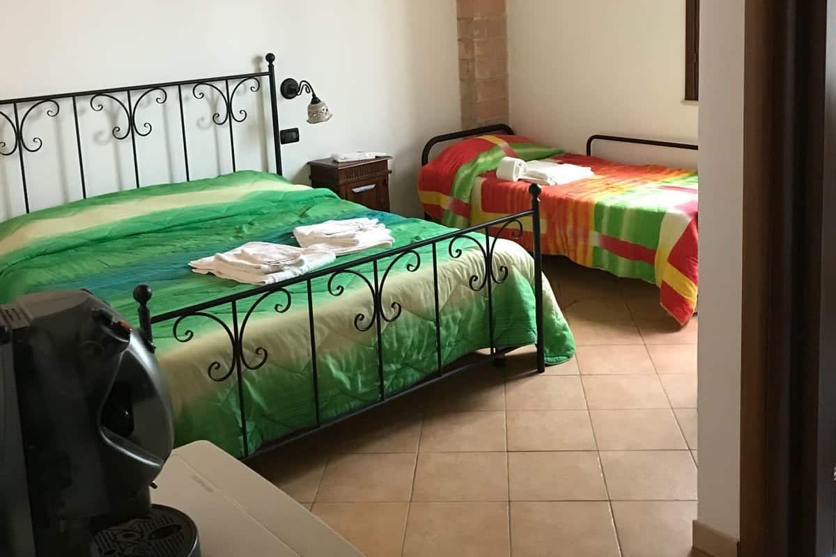 Ein Schlafzimmer mit zwei Betten, Holzboden, Backsteinwand und Fliesenboden.