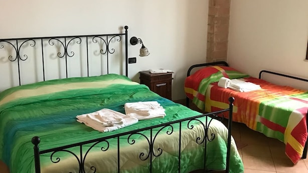 A bedroom with two beds, one larger and one smaller, both with metal frames and green bedding. - Egesta (Castellammare del Golfo)