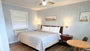 Une chambre à coucher comprenant un lit, des tables de chevet, un bureau et des chaises.
