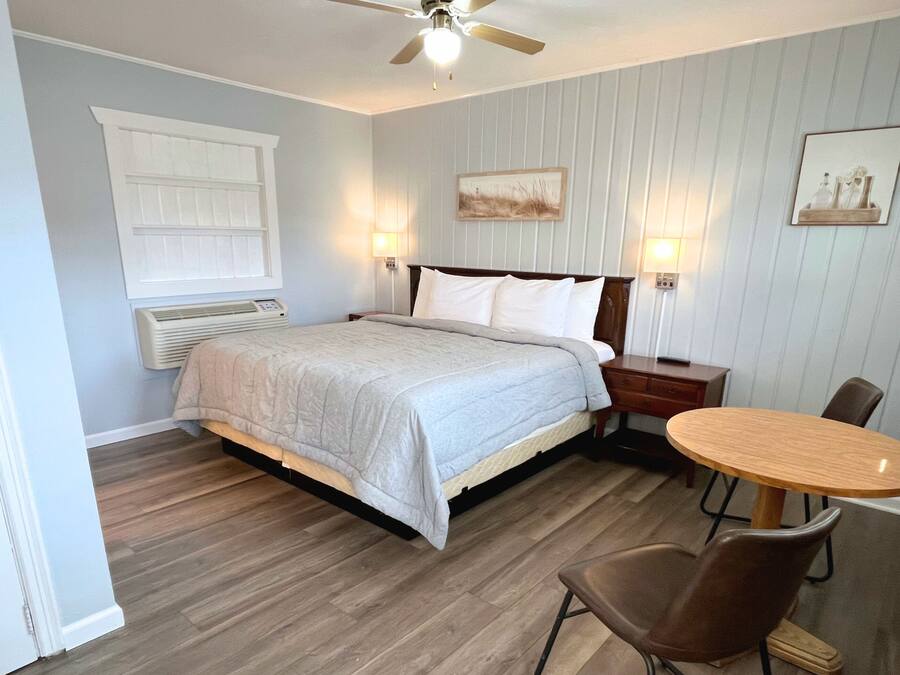 A bedroom with a bed, bedside tables, a desk, and chairs.