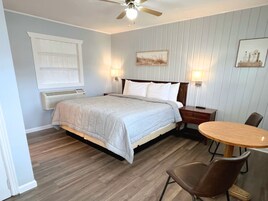 Quarto com cama, mesas de cabeceira, escrivaninha e cadeiras.
