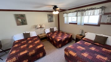 Quarto de hotel com duas camas, ventilador de teto, janela com cortinas e ar-condicionado fixado na parede.
