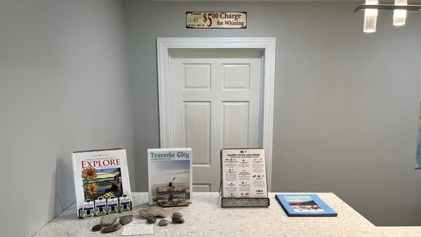 Un espace d’accueil avec un comptoir en pierre, une brochure intitulée « Activités et lieux à visiter », une brochure sur « Traverse City » et un panneau indiquant les restaurants et bars à proximité.