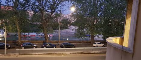 A view of a road with parked cars and trees.