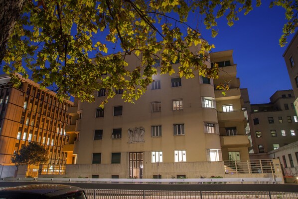 Un edificio de varios pisos con una entrada central, balcones y una estatua visible sobre la puerta.