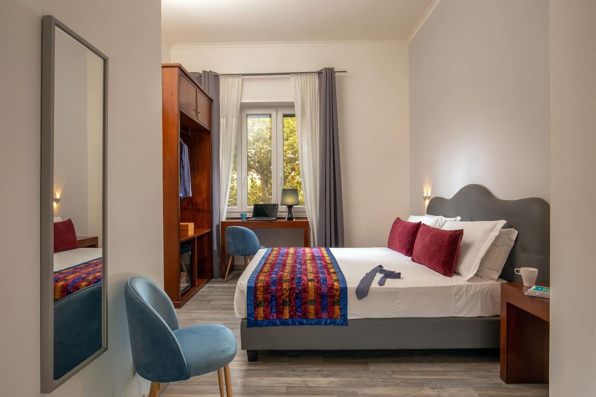 A bedroom with a bed, a desk, a chair, and a wardrobe.