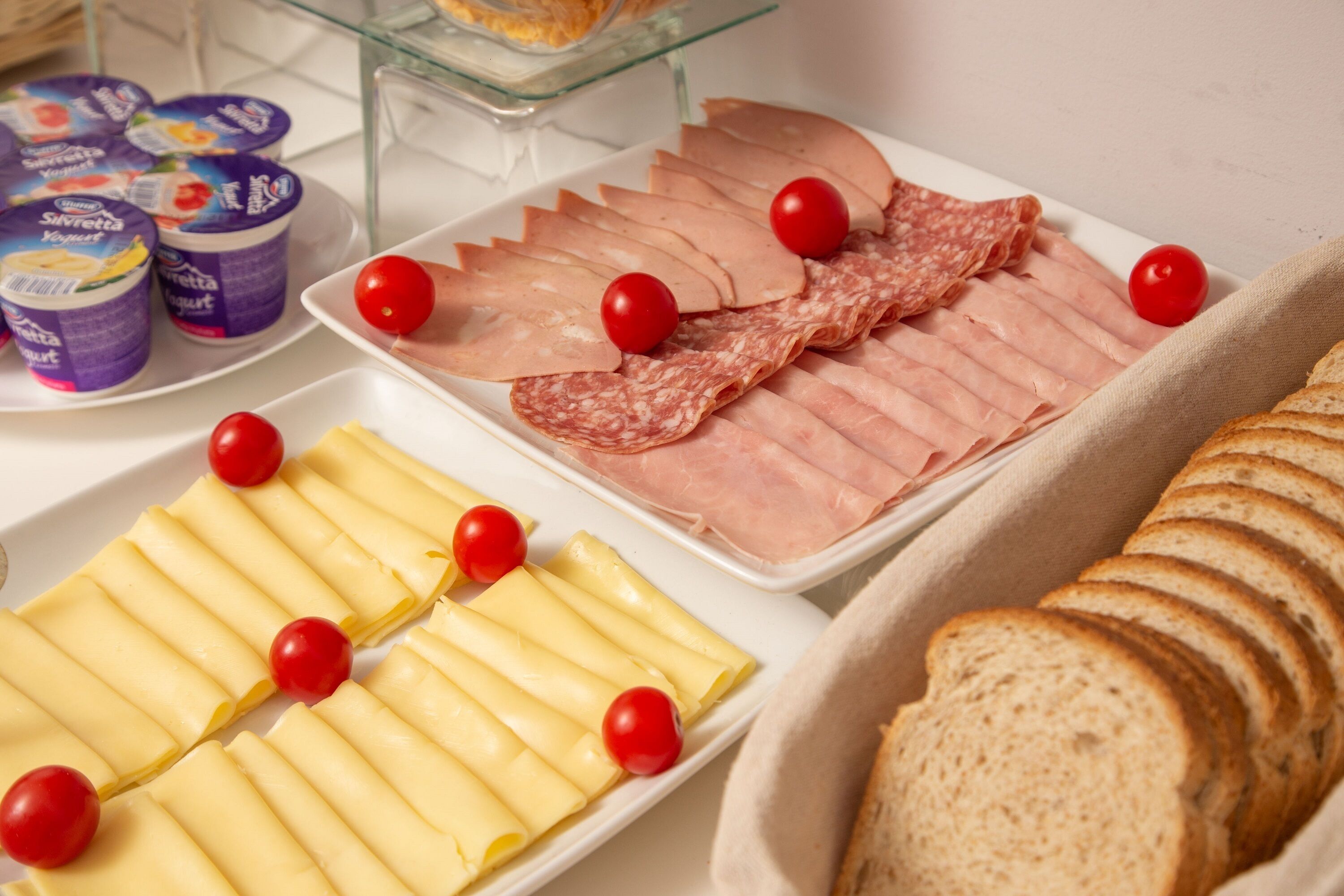 A buffet with various food items including sliced meats, cheese, and bread.