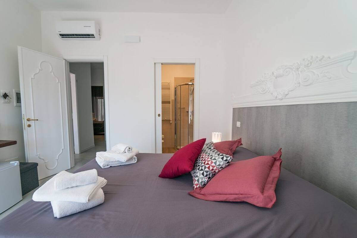 Camera d'albergo con un letto, una porta, un portascopevoli e un condizionatore d'aria.