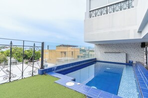 A rooftop swimming pool with clear blue water, surrounded by a metal railing and a small grassy area. - Hotel Boutique Adaz (Santa Marta)