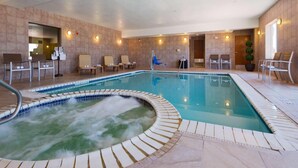 Una piscina con hidromasaje, sillas de descanso y suelo de baldosas.