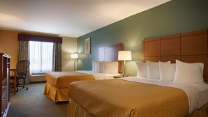 Habitación de hotel con dos camas, un escritorio y una silla.