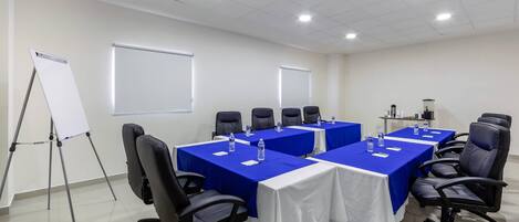 A conference room with a whiteboard, a projector screen, and a table with chairs.