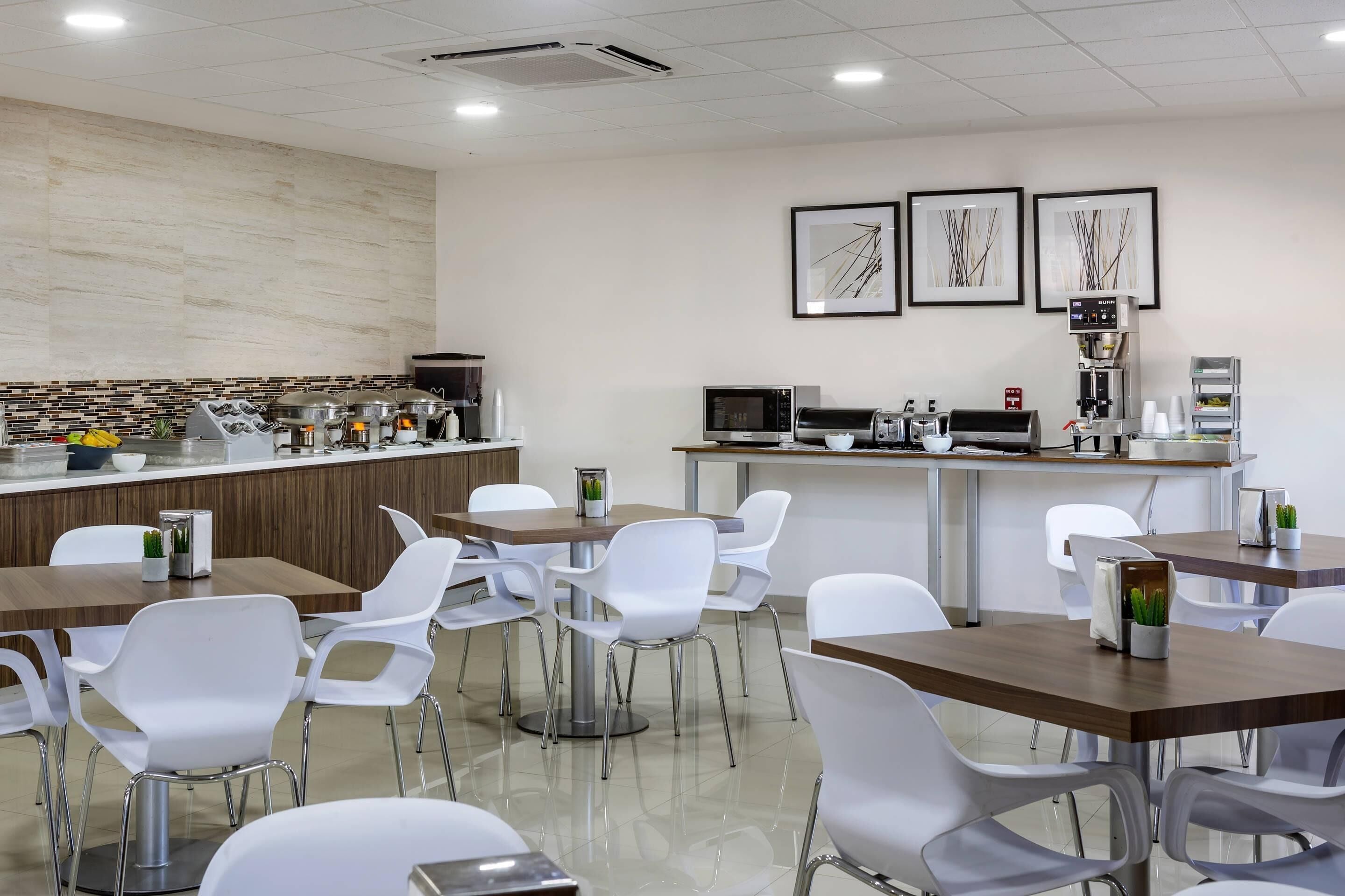 A modern cafe with white chairs, a counter with food items, and a coffee machine.