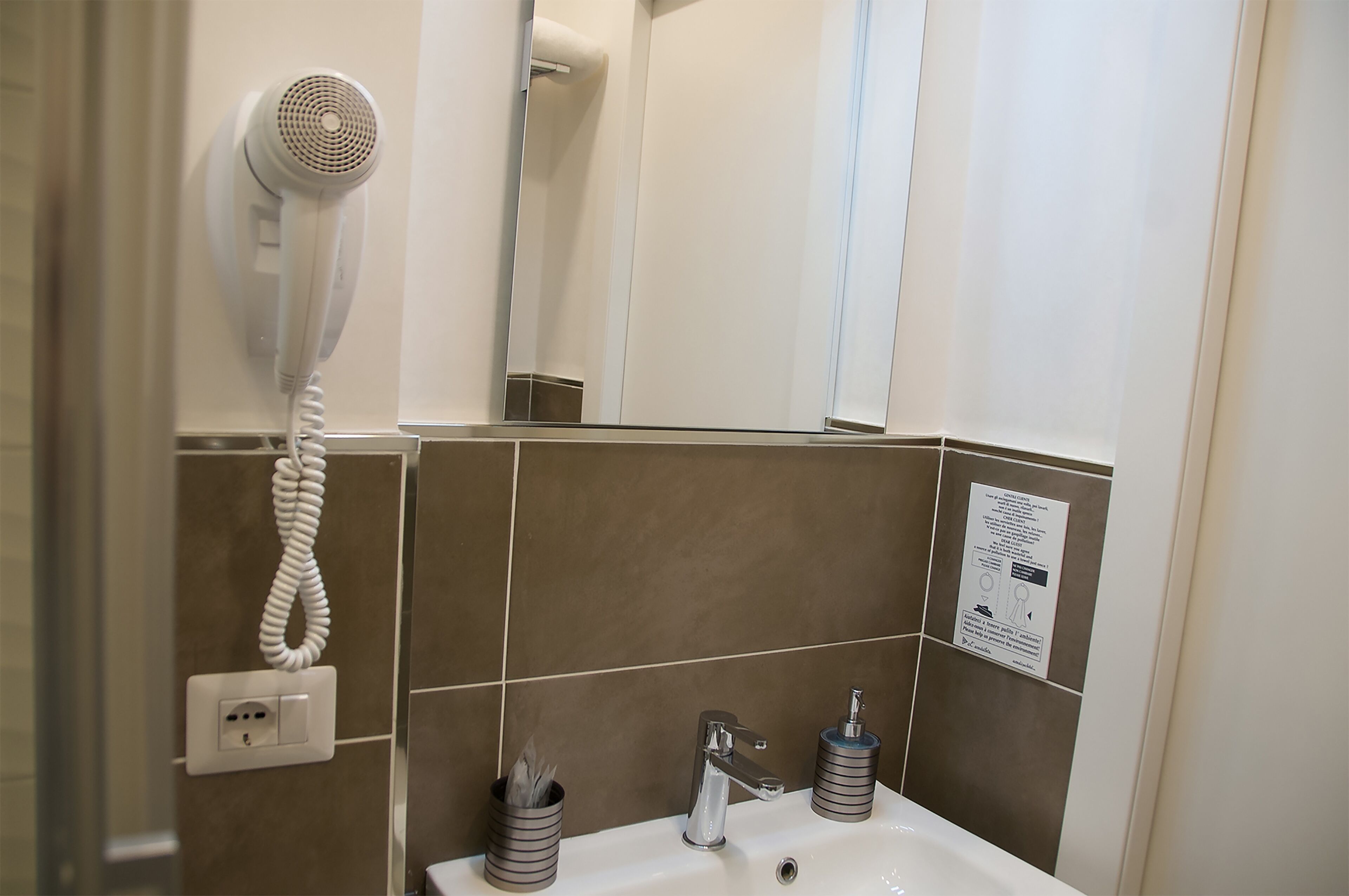 A bathroom with a hairdryer mounted on the wall, a sink with a faucet, and a mirror.