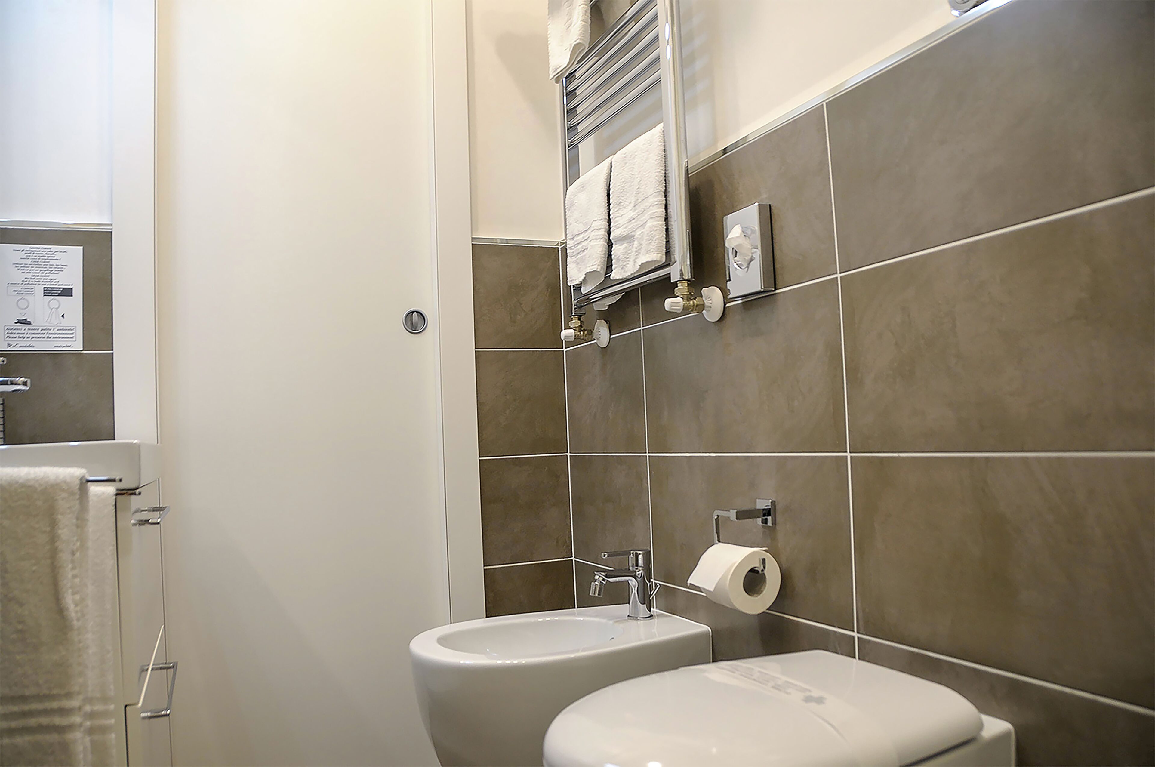 Une salle de bain équipée de toilettes, d’un lavabo et d’un porte-serviettes.