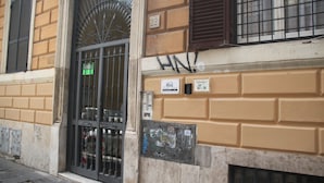 Fachada d'un edifici amb una reixa metàl·lica, un rètol amb el número 22 i uns grafits.