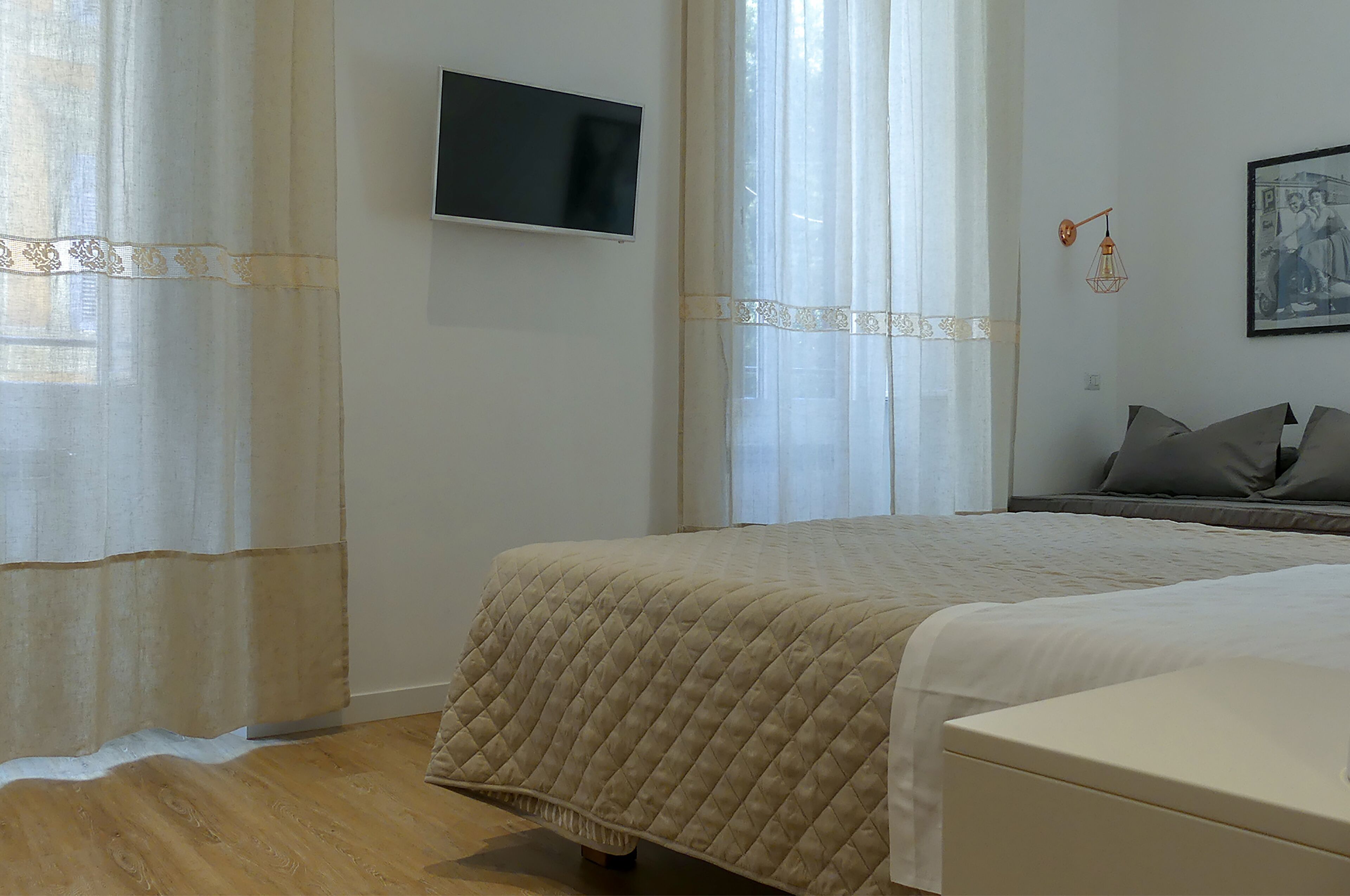 Une chambre à coucher avec un lit, un téléviseur fixé au mur et un tableau.