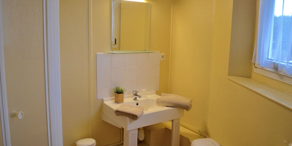 Ein kleines Badezimmer mit einem weißen Waschbecken, einem Spiegel und einem Fenster.