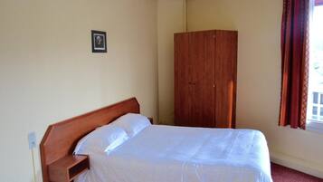 Un dormitorio con una cama individual, un armario de madera y una pequeña imagen en la pared.