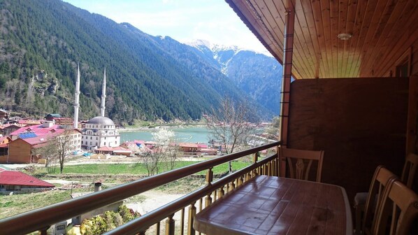 Un balcon en bois offrant une vue sur une mosquée, des montagnes et une rivière.