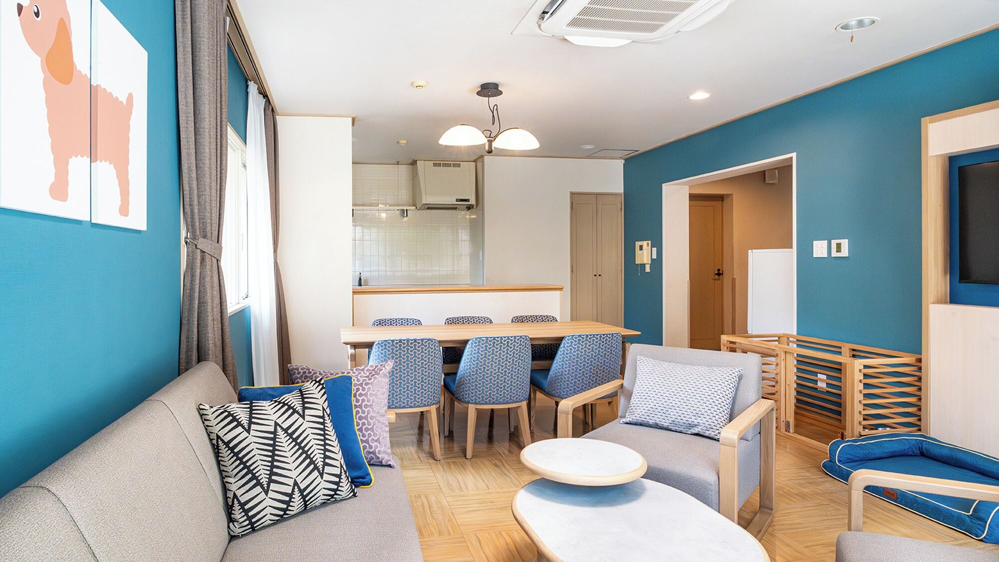 Un salon moderne avec un canapé, des coussins à motifs, une table basse ronde et un coin repas comprenant des chaises et une table.