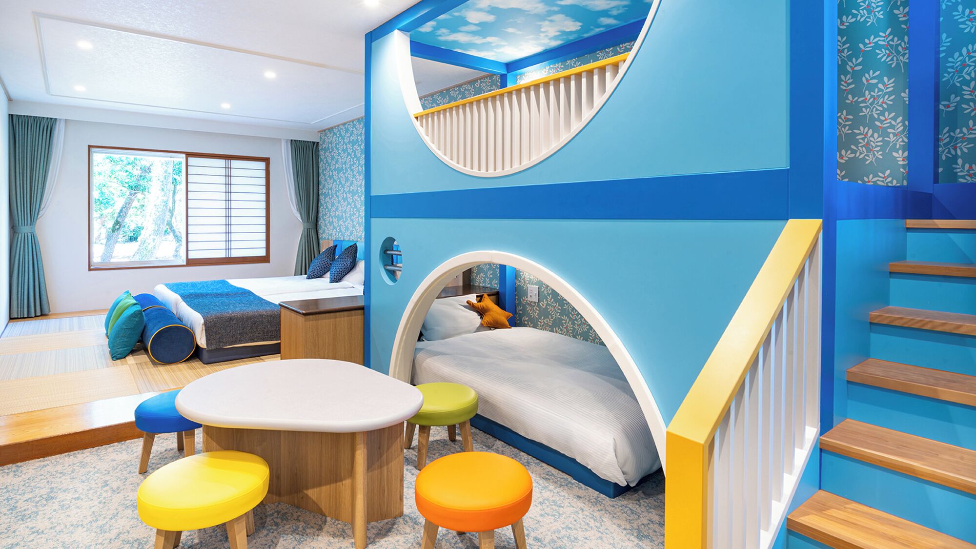 Un espace de jeux pour enfants avec un toboggan, un lit, une table et des tabourets colorés.