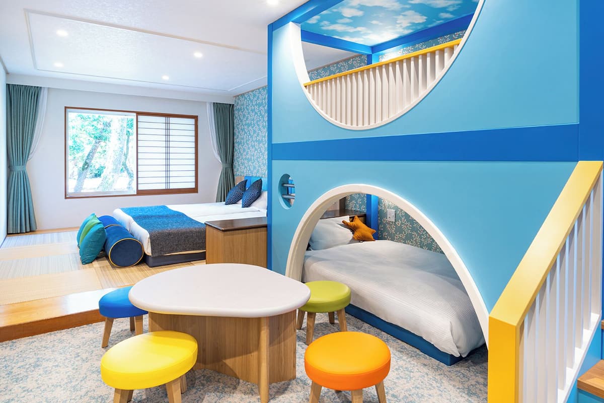A children's play area with a slide, a bed, a table, and colorful stools.