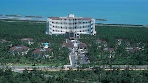 A large hotel with a central courtyard, surrounded by lush greenery and a view of the ocean. - Cottage Himuka (Miyazaki)