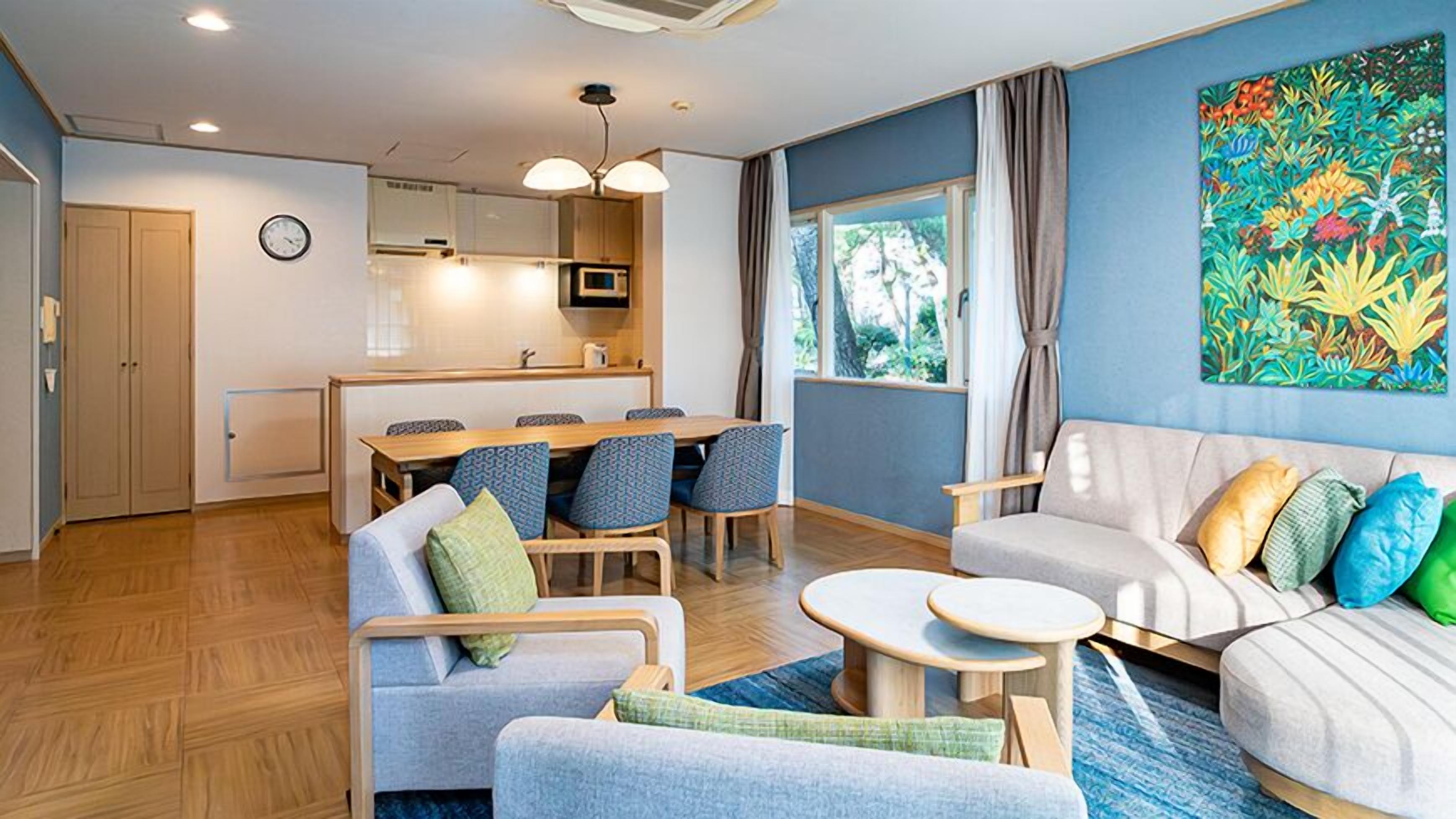 Un salon moderne comprenant un canapé, une table à manger avec des chaises, un coin cuisine et une grande fenêtre avec des rideaux.