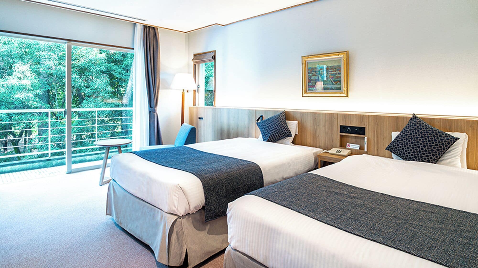 Une chambre d’hôtel avec deux lits, une grande fenêtre, un bureau et une chaise.