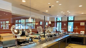 A buffet setup with multiple serving stations, overhead lighting, and large windows. - Cottage Himuka (Miyazaki)