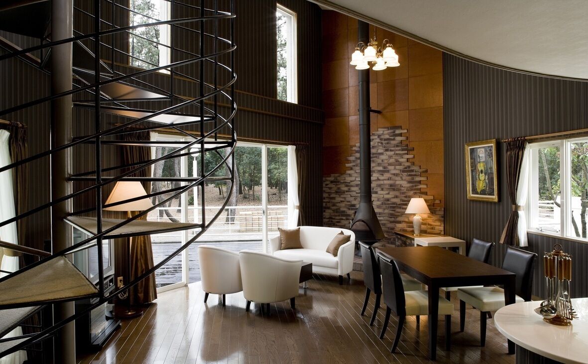 A modern interior with a spiral staircase, a fireplace, a dining area, and large windows.