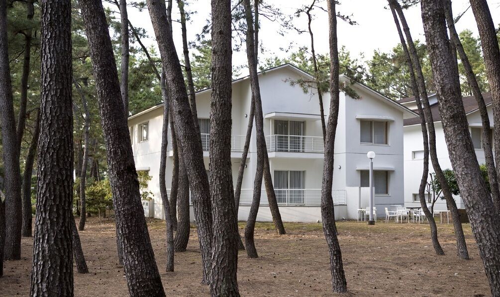 Un bâtiment à deux étages doté d’un balcon, entouré d’arbres.