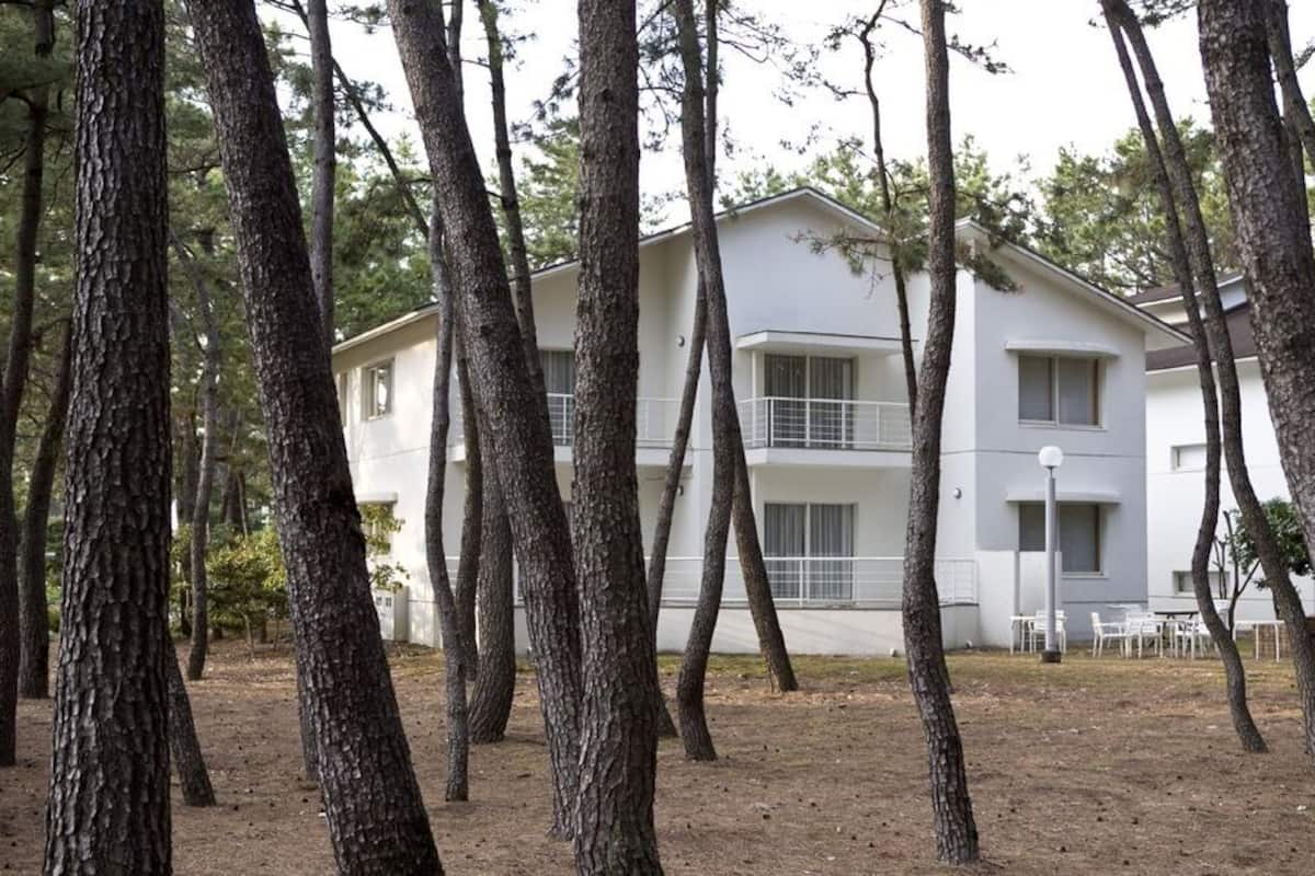 A two-story building with a balcony, surrounded by trees.