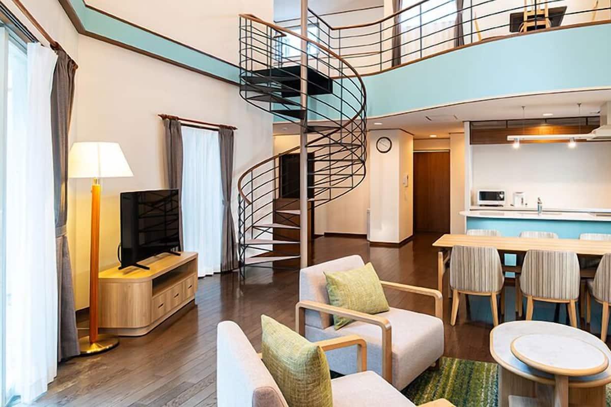 A modern interior with a spiral staircase, a dining area, and a kitchenette.
