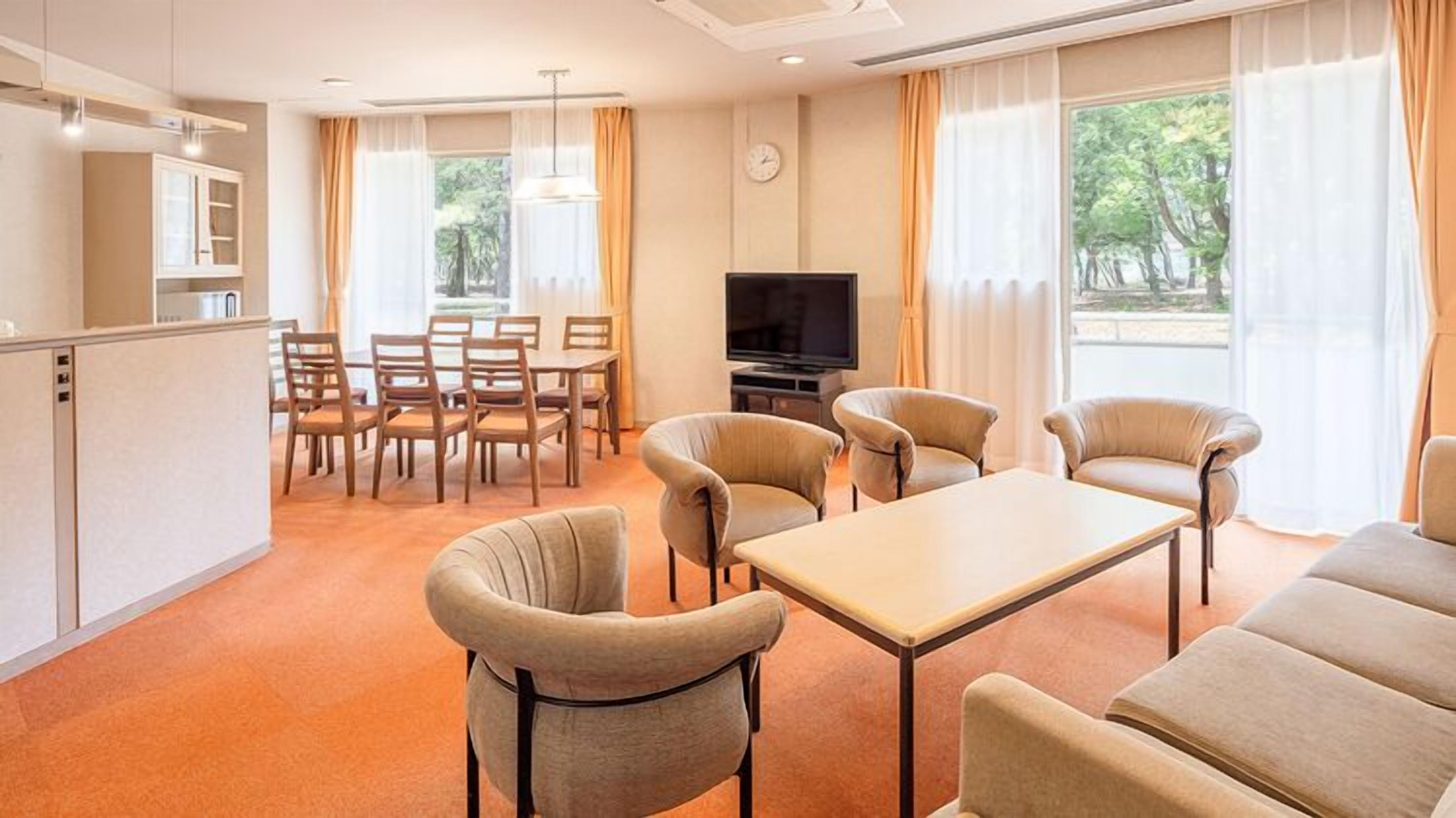 Une chambre d’hôtel avec un coin repas, une télévision et un canapé.