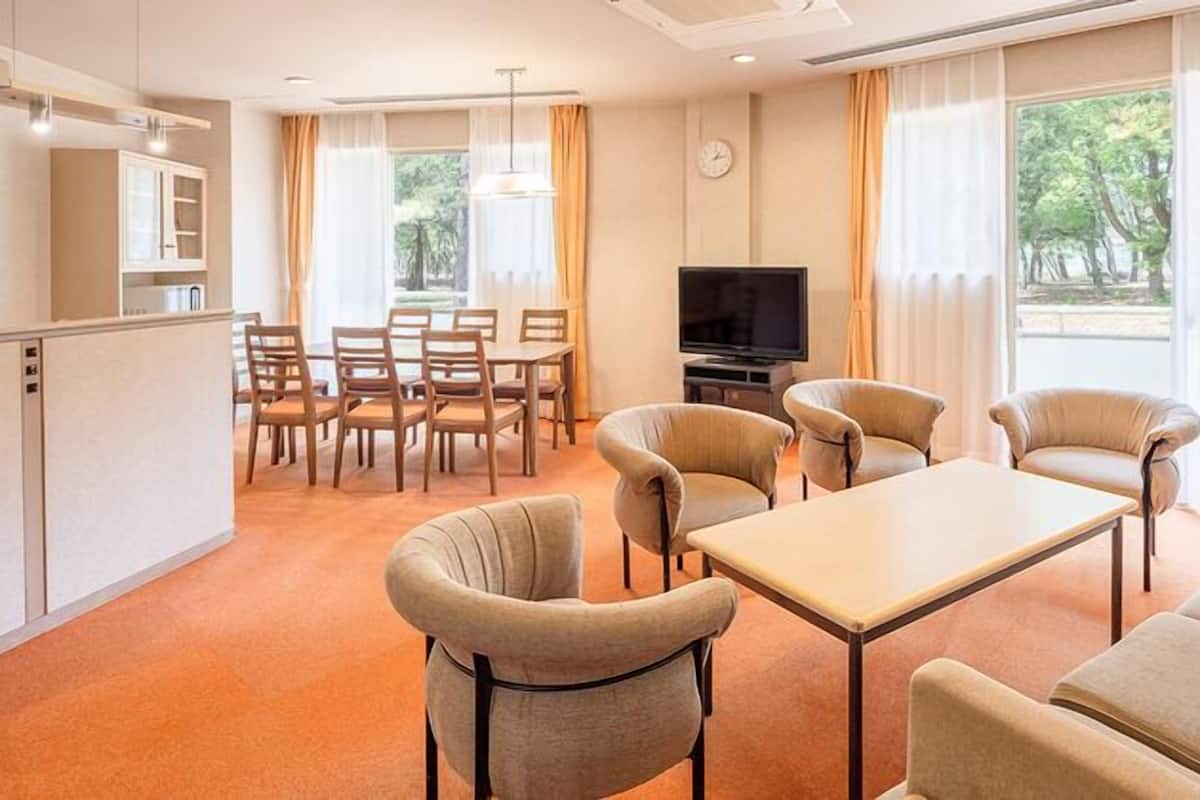 A hotel room with a dining area, a TV, and a sofa.