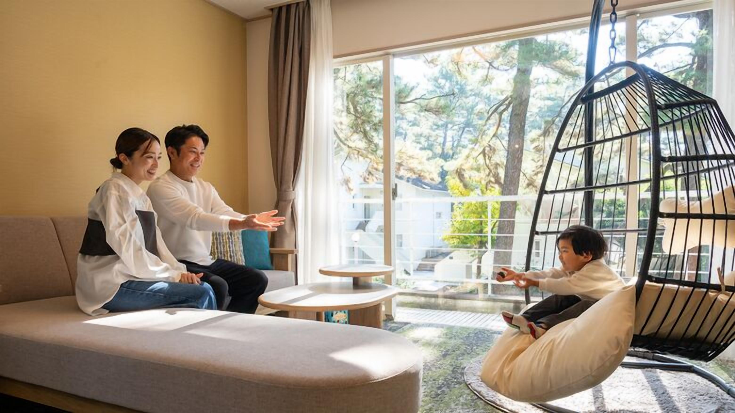 Un salon moderne avec un canapé, un fauteuil suspendu et une table en verre.