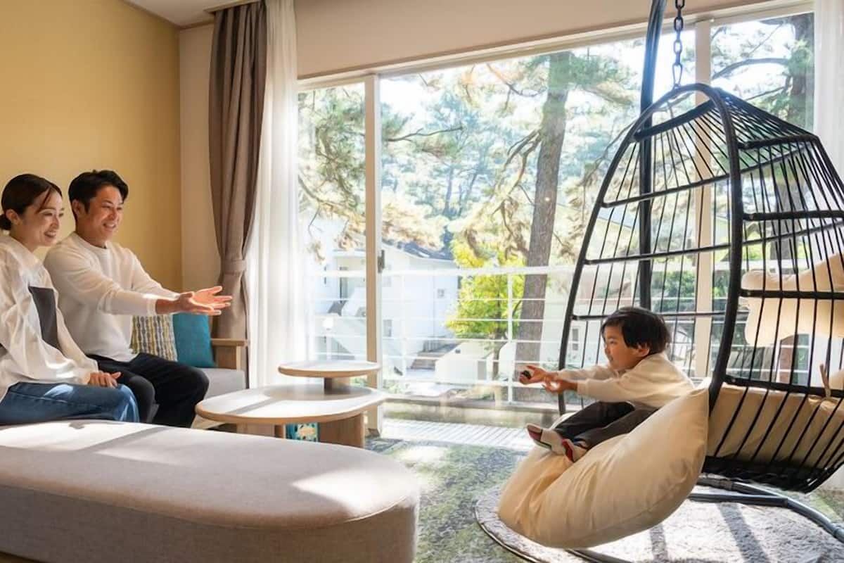 A modern living room with a sofa, a hanging chair, and a glass table.
