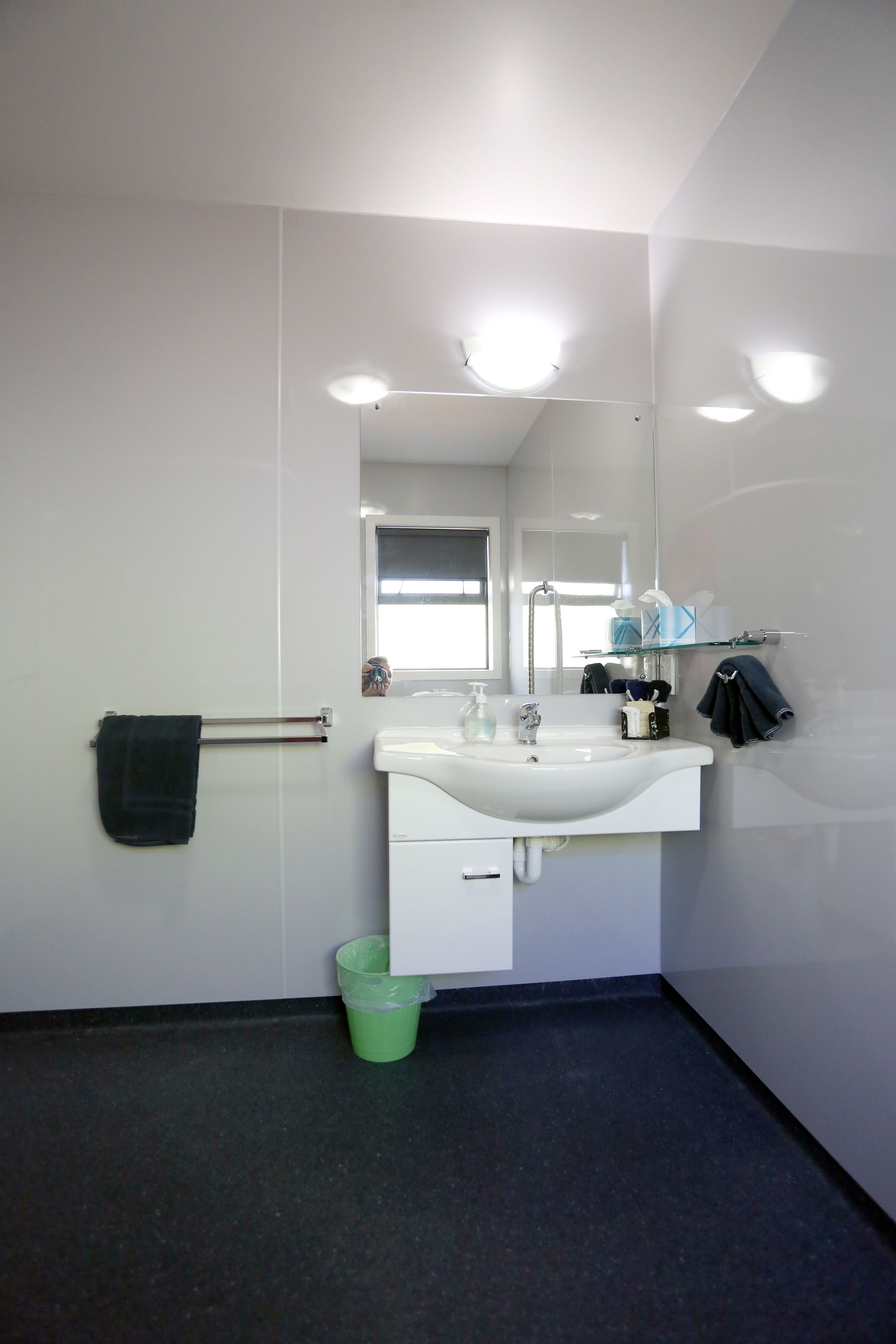 Een badkamer met een wit wastafelmeubel, spiegel en handdoekrek.