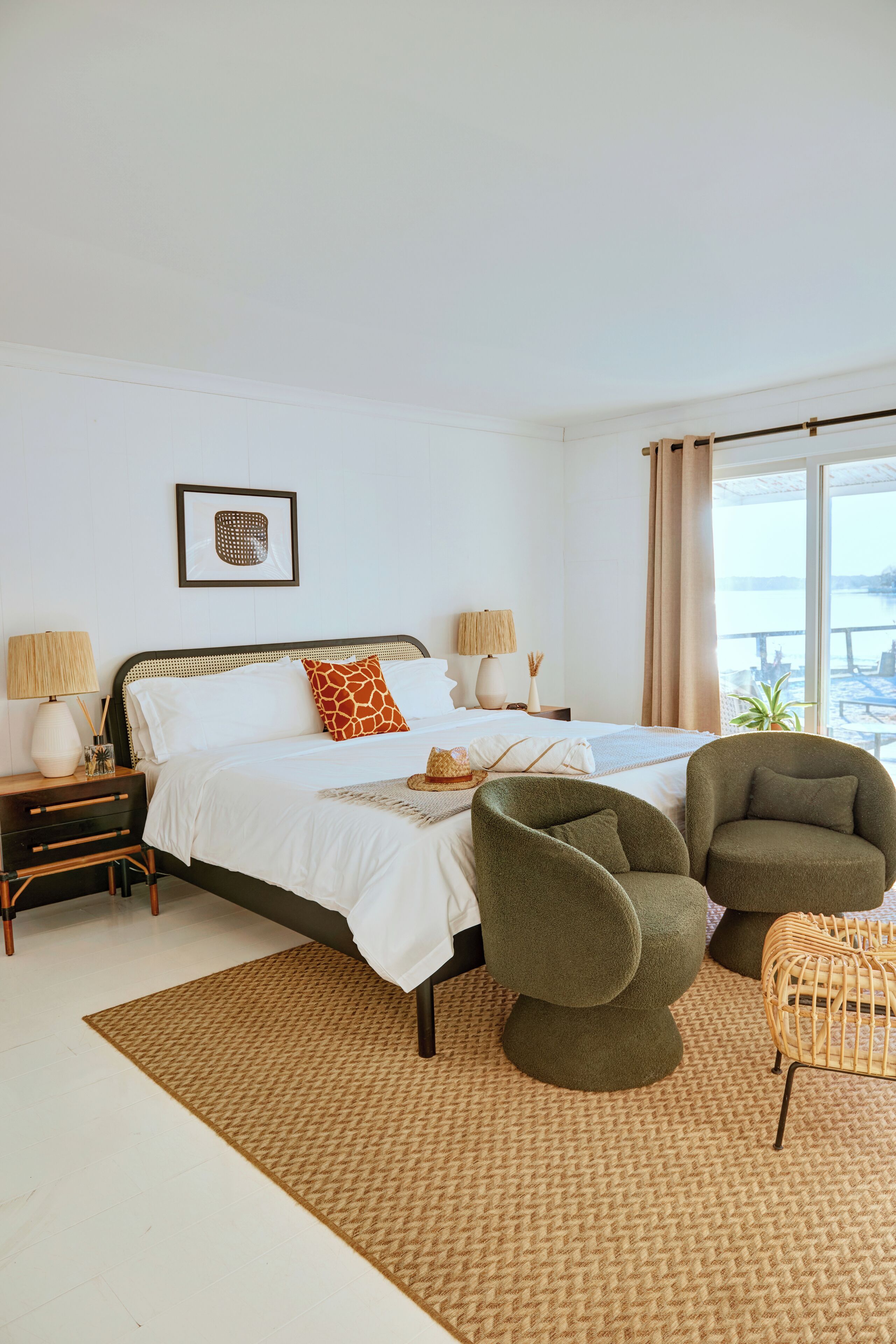 Quarto com cama, duas mesas de cabeceira, uma cadeira, janela com vista e um quadro na parede.